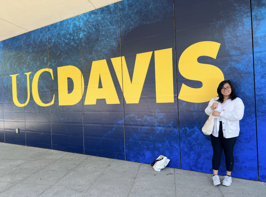 Sam Wai ‘25 standing in front of the UC Davis sign at the University of California, Davis during a visit to its campus.